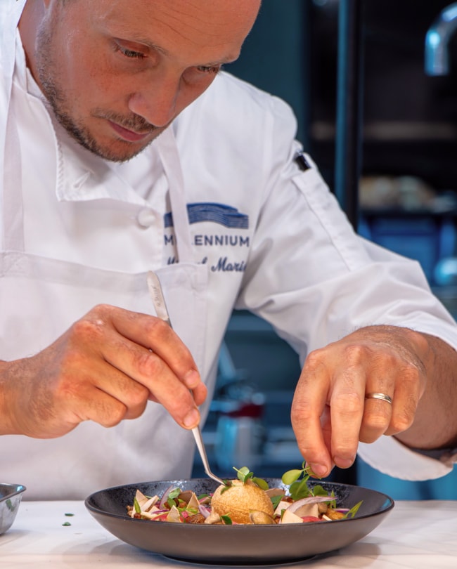 Millennium chef carefully plating a dish