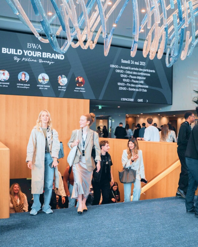 Participants badgés dans le Lobby sous l’écran LED affichant le programme