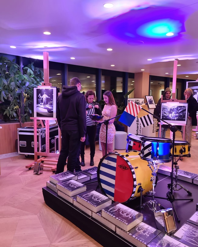 Galerie d’art aménagée pour une exposition-événement avec batterie et livres