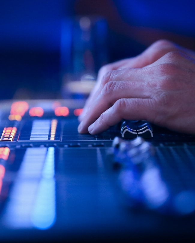 Main d’un technicien sur une console de mixage en régie