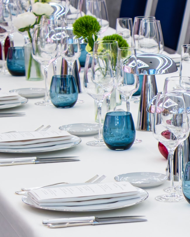 Table de réception dressée : verres en cristal et verres bleus, fleurs blanches
