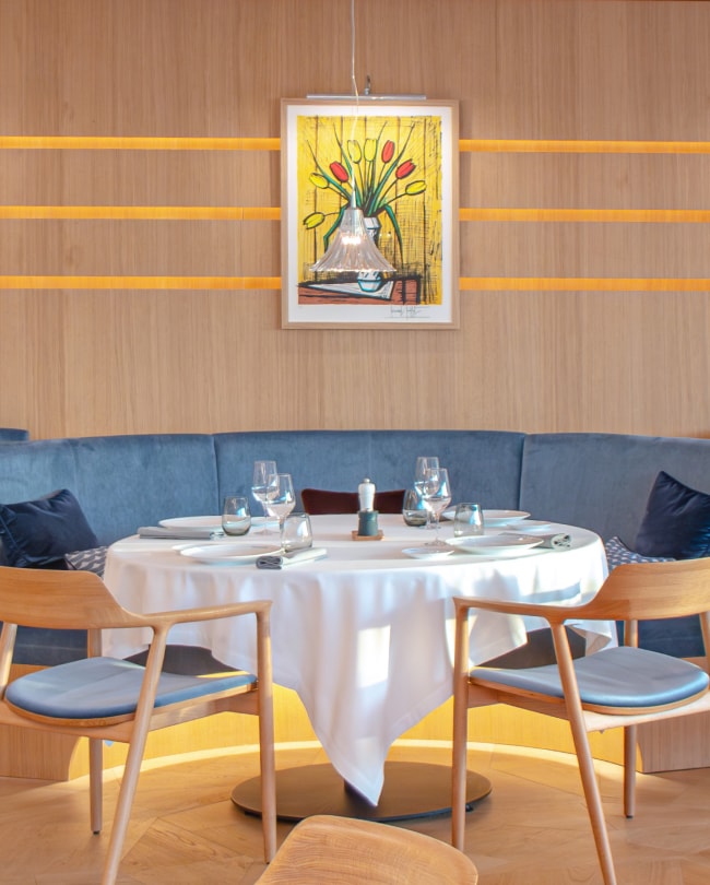 Round table laid beside a blue banquette at the Brasserie